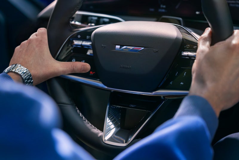 Close-up of a Man About to Press the V-Button on the 2026 OPTIQ-V Steering Wheel | Ken Barrett Chevrolet Cadillac in BATAVIA NY